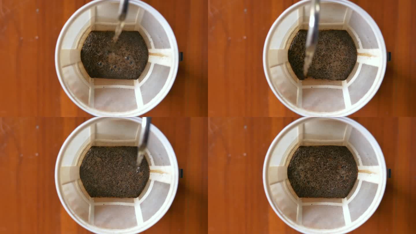 俯视图通过将溢出的热水倒入研磨的咖啡上准备过滤器，倒在咖啡上酿造，滴漏咖啡。4 k的视频