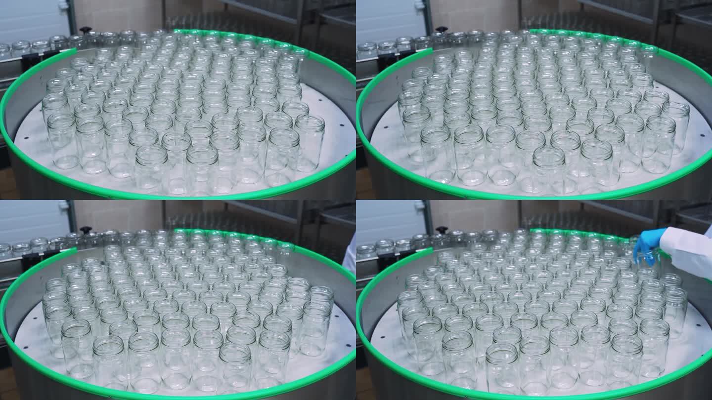 在食品厂，玻璃罐被送入传送带。婴儿食品厂、乳品厂、牛奶或酸奶装瓶店。玻璃罐移动到自动产品灌装线上。