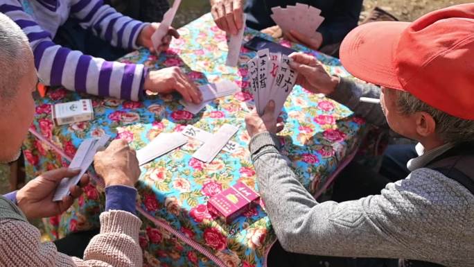 一群老年人围在一起打纸牌，南方纸牌
