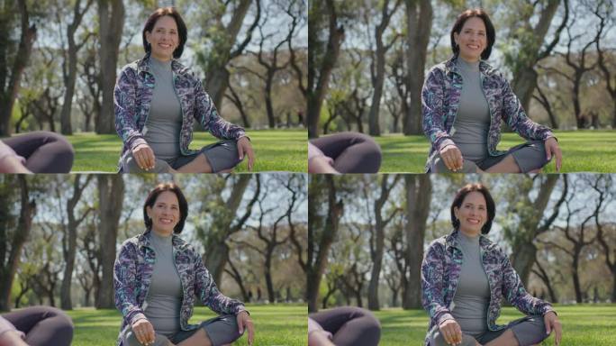 微笑的成熟女人在公园瑜伽课上摆姿势拍照