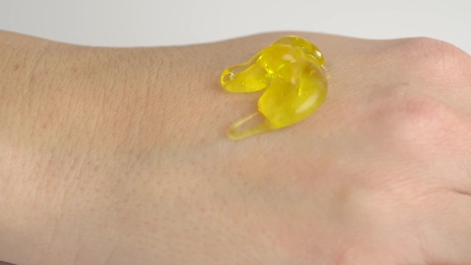 黄色透明的脱皮凝胶与泡沫倒在打开的手。护肤理念