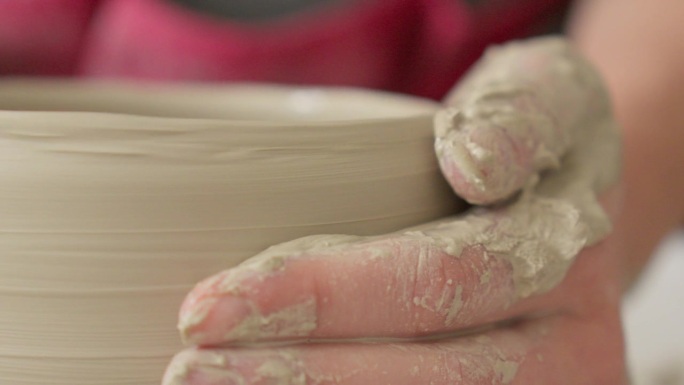 陶艺师用双手在滚轮上打磨碗壁