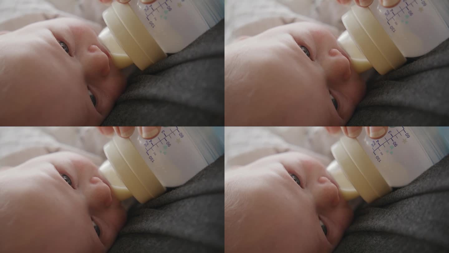 可爱的小男孩被妈妈用奶瓶喂牛奶的手持特写
