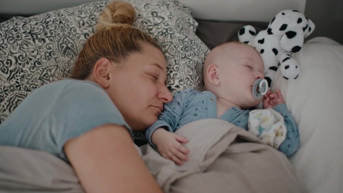妈妈和宝宝在家里的床上睡觉的高角度手持拍摄