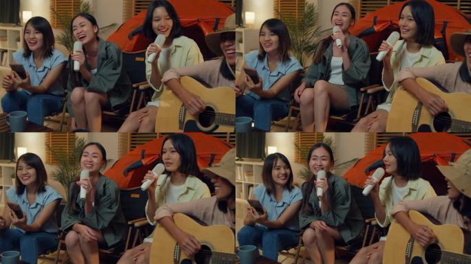 一群亚洲女性朋友晚上在家里的客厅里露营，一边唱歌一边用手机自拍视频通话。快乐的女人边说边笑，享受休闲