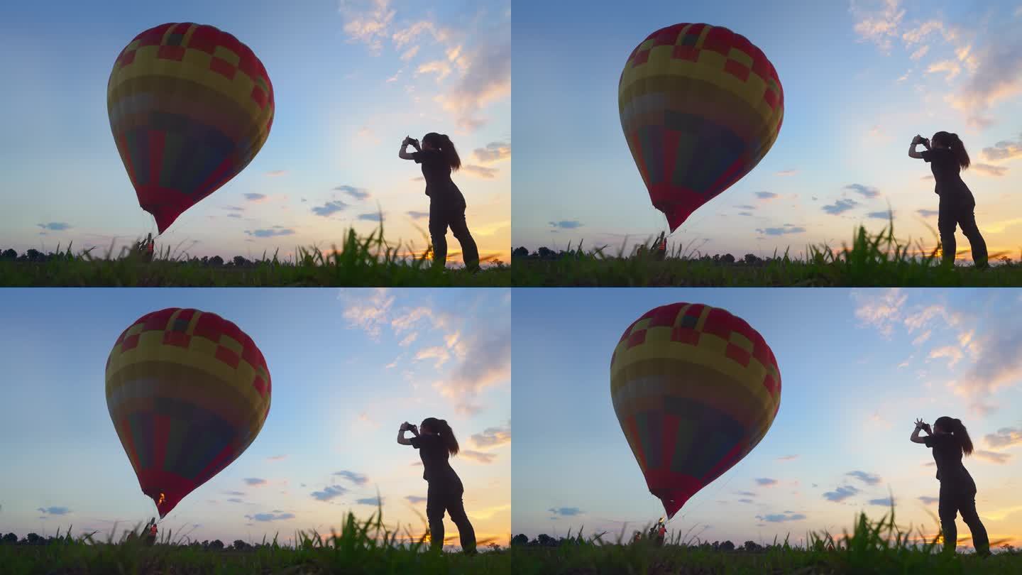 少女游客享受在日落时拍摄热气球