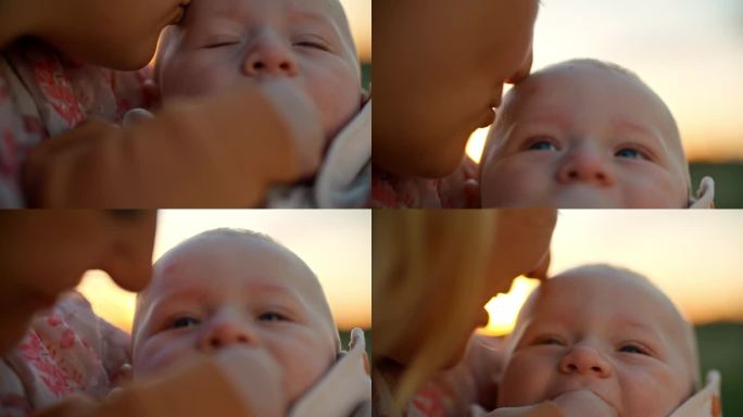 SLO - MO手持拍摄的剪短的母亲在日落时亲吻欢快的男婴额头的照片