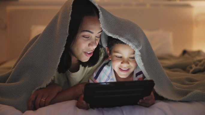 晚上，卧室里和妈妈和儿子在一起，平板电脑或打字与讲故事或在一起。家庭，妈妈或孩子与科技或家庭与蹒跚学
