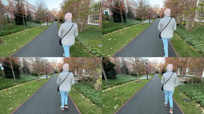 一个女人独自走过哈佛大学的花园和建筑