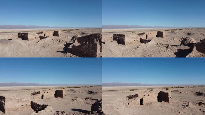 在干燥的沙漠景观中，镜头缓慢地移动在破旧的泥砖土坯建筑上，天空湛蓝，没有云
