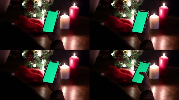 使用绿屏的智能手机，夜晚的圣诞树和蜡烛
