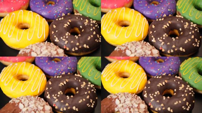 在黑色背景上旋转许多不同口味的彩色甜甜圈。