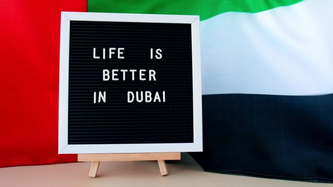 框架文字迪拜的生活更美好，背景是挥舞着由丝绸制成的阿联酋国旗。阿联酋国旗，以旅游和旅行为概念。邀请贺
