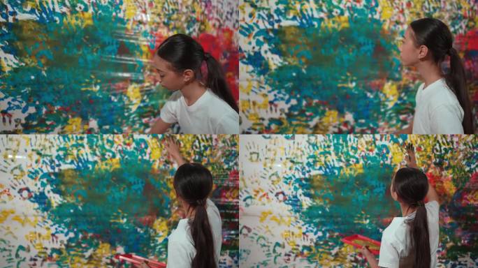 年轻的女孩拿着彩绘托盘和彩绘墙。启迪