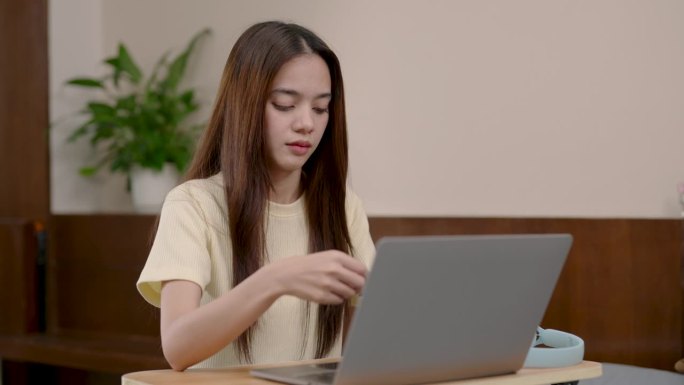 亚洲女子坐在笔记本电脑前，女子在社交媒体上网购，女子拿出信用卡，在支付终端输入信用卡信息，扣掉信用卡