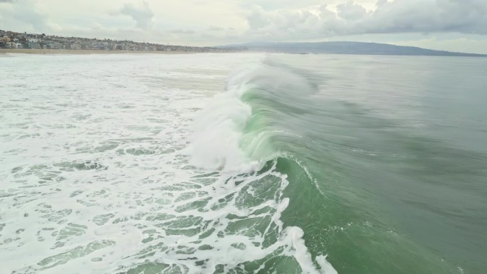 孤独的冲浪者熟练地驾驭巨大的波浪，当它到达海滩时失去平衡
