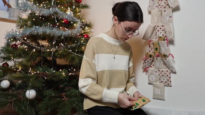 一个十几岁的女孩从降临节日历中打开一个圣诞惊喜礼物。