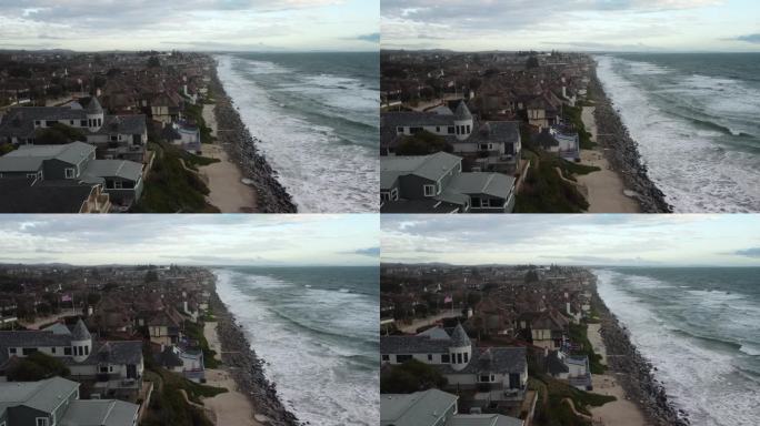 4K鸟瞰图无人机拍摄的南加州一个城市海滩海岸线，蓝色的太平洋，海浪涌进来，海滩上有漂亮的房子，强风正