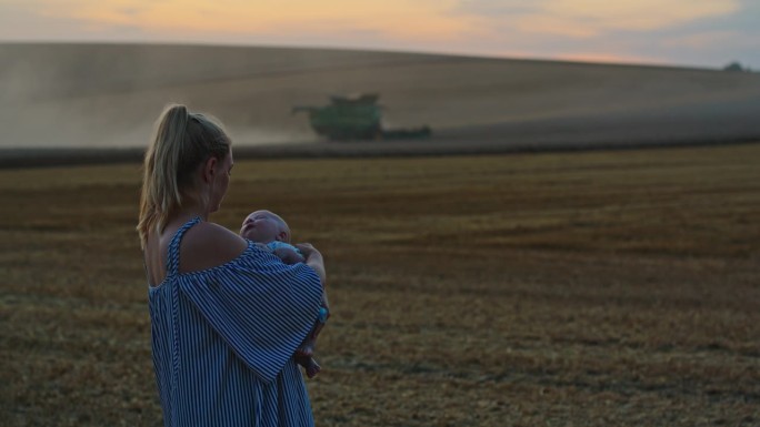 黄金时段，农妇抱着儿子在拖拉机上犁地的镜头