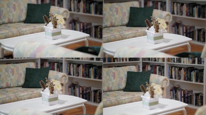 老式的客厅家具，一张沙发和一张咖啡桌，周围是拥挤的书架上的书。