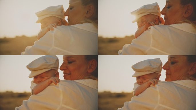 在晴朗的晴天，快乐的母亲抱着熟睡的男婴在麦田里