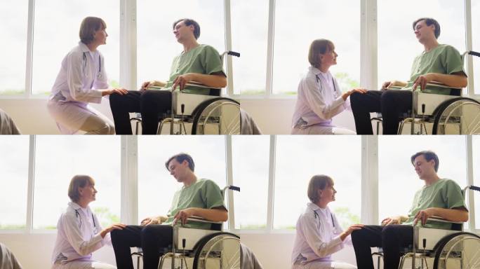 在有玻璃窗和温暖光线的房间里，资深白人女医生和坐在轮椅上的年轻病人交谈。医生试图安抚因病痛而痛苦不堪