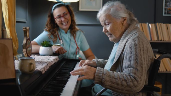 一位坐在轮椅上的老祖母在弹钢琴，她的医生或看护人在听她弹琴