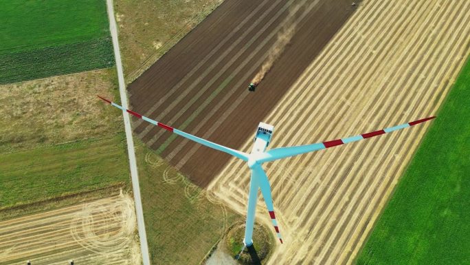 空中收获风:无人机视图旋转涡轮机在农民耕地。鸟瞰图