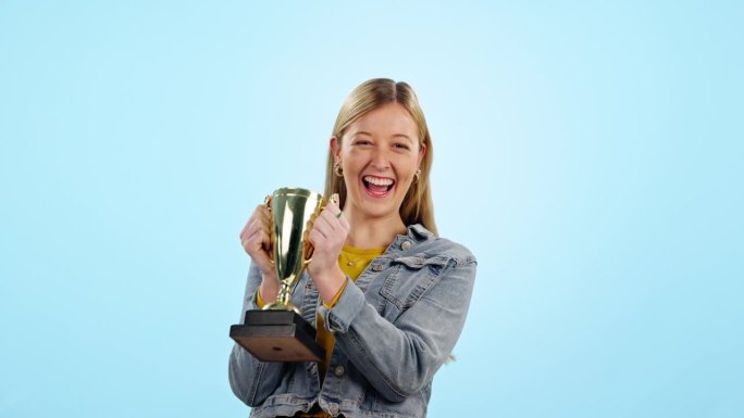 女子，在学习成绩，进球或获胜的蓝色背景的工作室奖杯庆祝和微笑。女孩，学生，在学院，大学或学院获得奖品