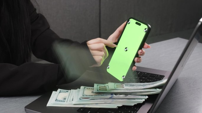 女人轻敲屏幕，每轻敲一次，钱就会出现。一个女人的手在手机上，屏幕是绿色的，便于抄写。贷款、存款、商业