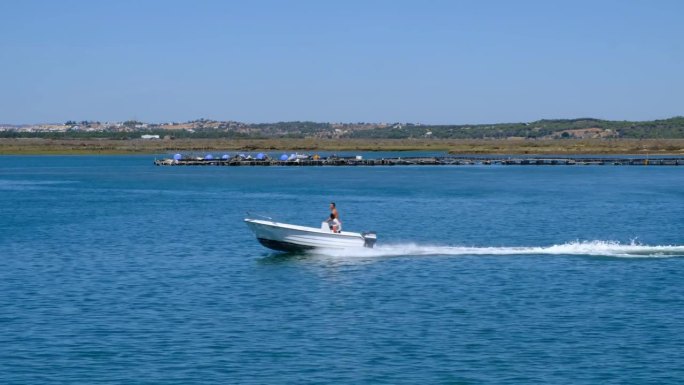 2023年8月16日，西班牙韦尔瓦的克里斯蒂娜岛:游艇在克里斯蒂娜岛开曼岬海滩前的海面上航行