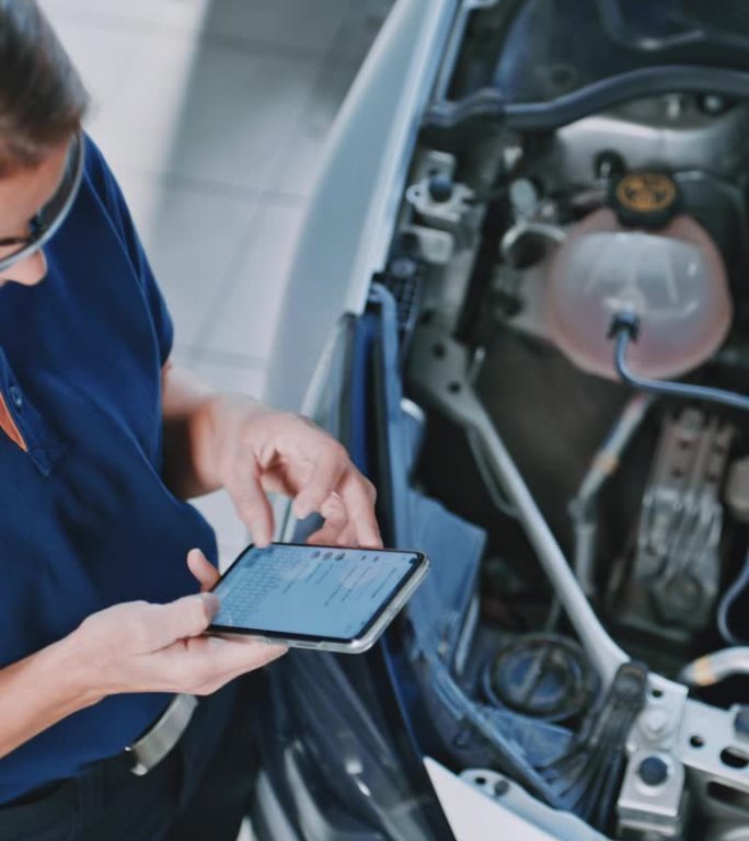 女修理工在汽车发动机前使用智能手机
