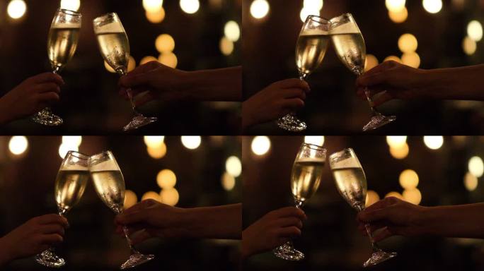 两只手干杯碰杯庆祝的超慢动作，夜晚的光斑