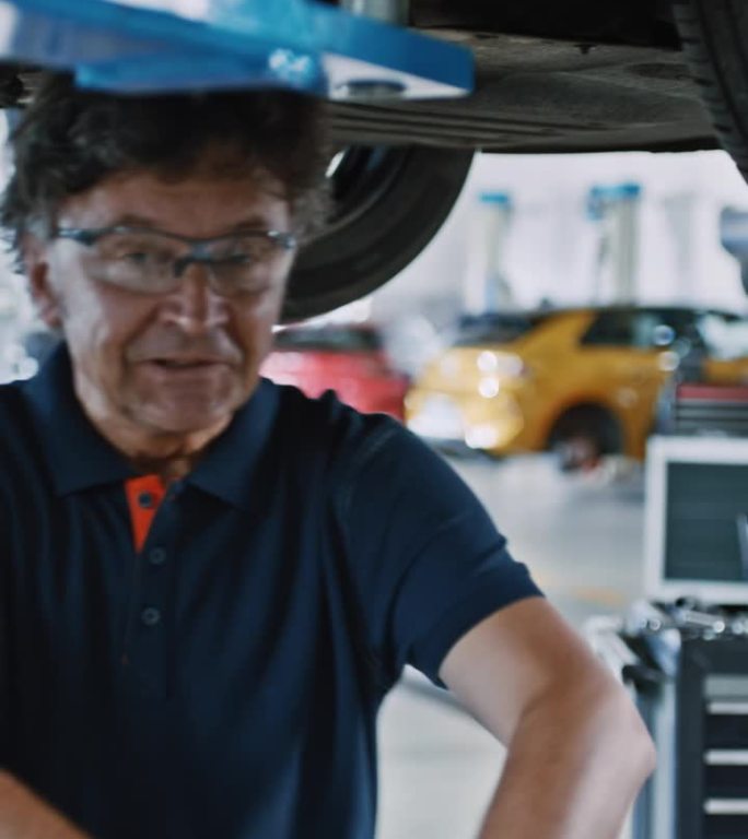 肖像男机械师在汽车修理店用灯检查汽车