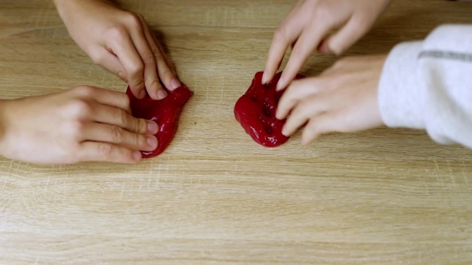 孩子们的手在玩滑溜溜的橡皮泥。孩子们的手在家里的桌子上玩着黏有弹性的橡胶泥。高品质4k画面