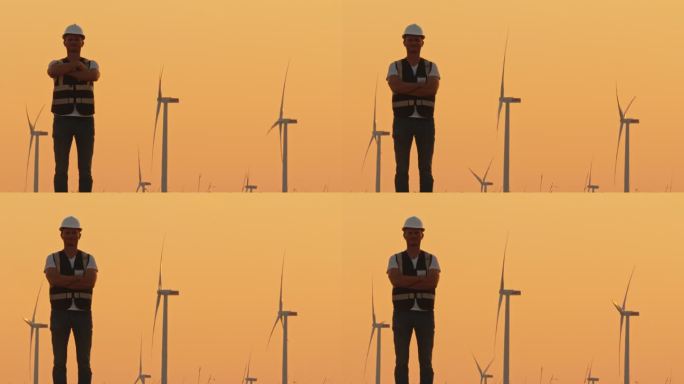 SLO MO工程师在黄昏的风力涡轮机前双臂交叉沉思
