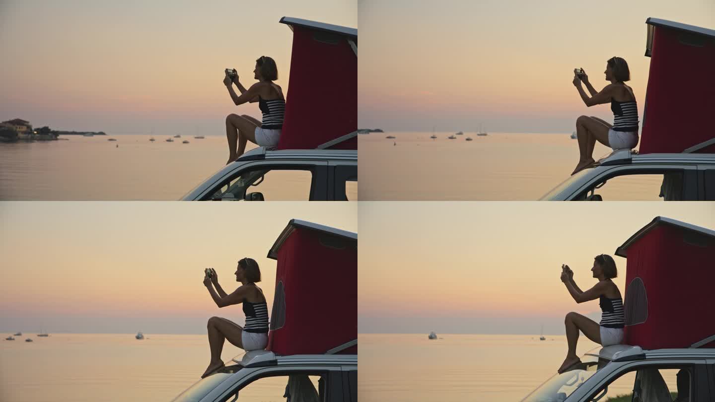 日落时分坐在面包车上用手机拍照的女子的慢镜头镜头