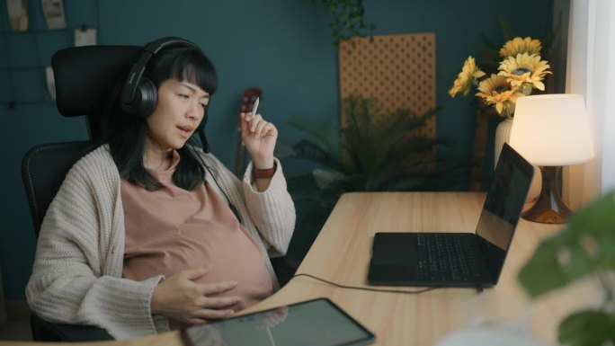 孕妇在家用平板电脑工作的侧面图。做自由职业者和远程工作。