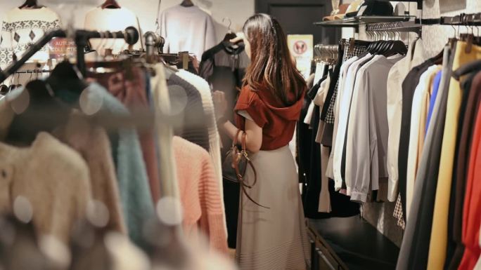 在日本大阪，一名日本妇女正在挑选冬季服装套装，并在时装店购物