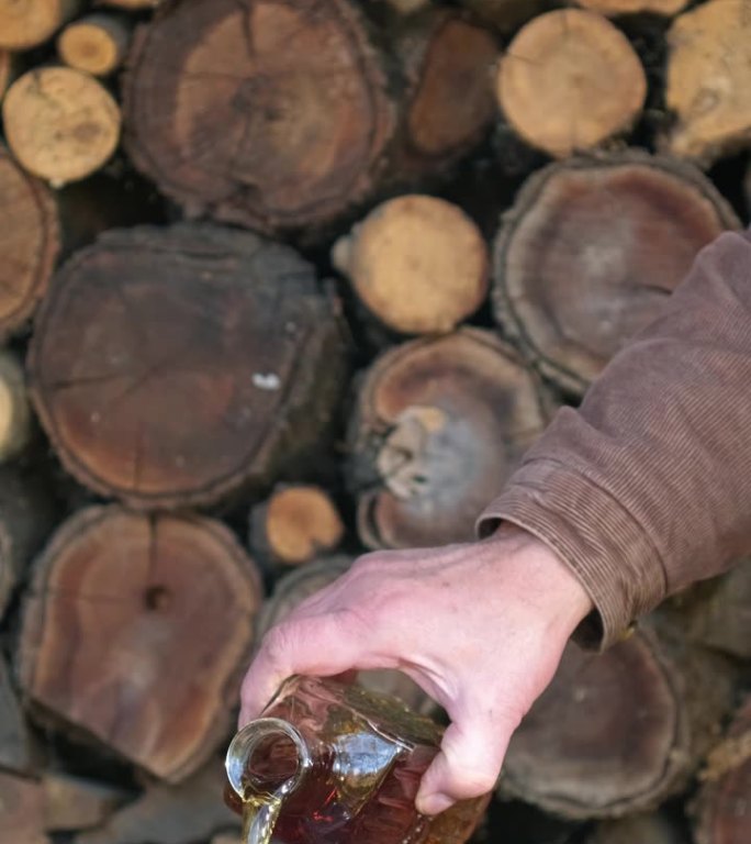 一杯加冰的威士忌放在木桌上，背景是乡村风情