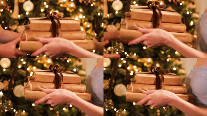 以装饰过的冷杉树为背景，妇女赠送和接受圣诞礼物的特写。女士穿着时髦的晚礼服，用丝带把一摞书送给她最好