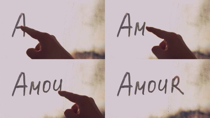 女人的手指在泥泞的玻璃上用英语写着法语“Amour”是“爱”