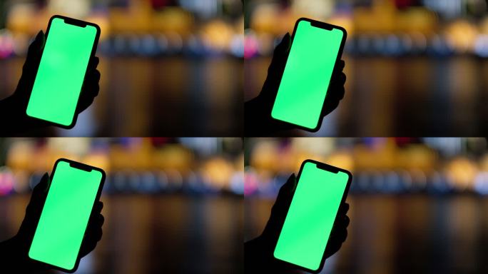 手展示绿屏的智能手机，五颜六色城市的光斑
