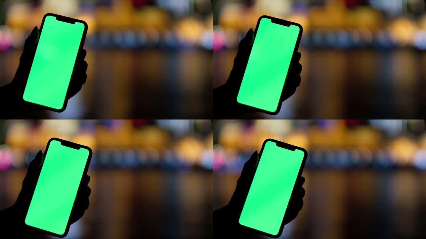 手展示绿屏的智能手机，五颜六色城市的光斑