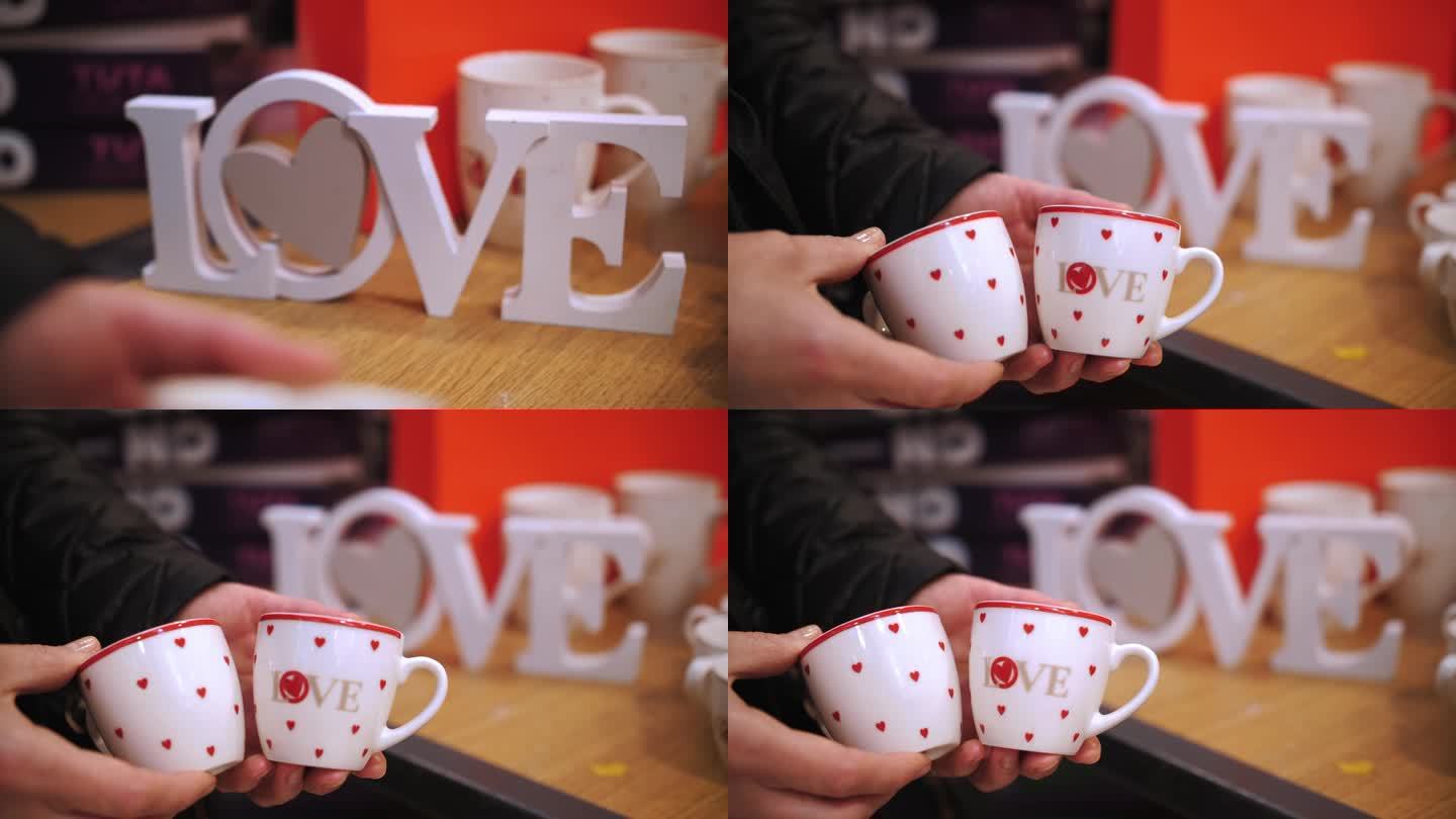 情人节。特写镜头。木制的情书，在背景里。手里拿着小小的咖啡杯，红心上写着爱。作为一种感情和爱的表达。