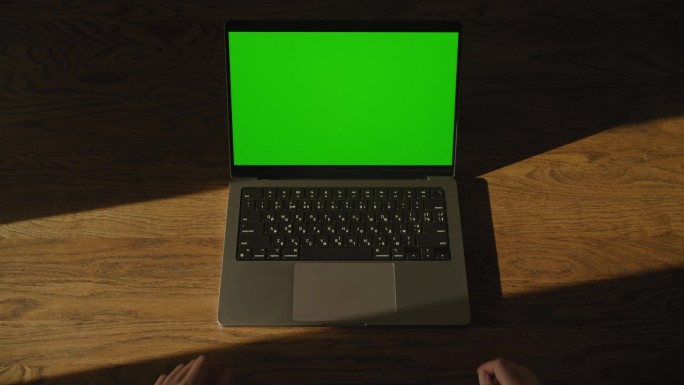 女人双手放在笔记本电脑键盘上，屏幕是铬绿的，然后离开画面