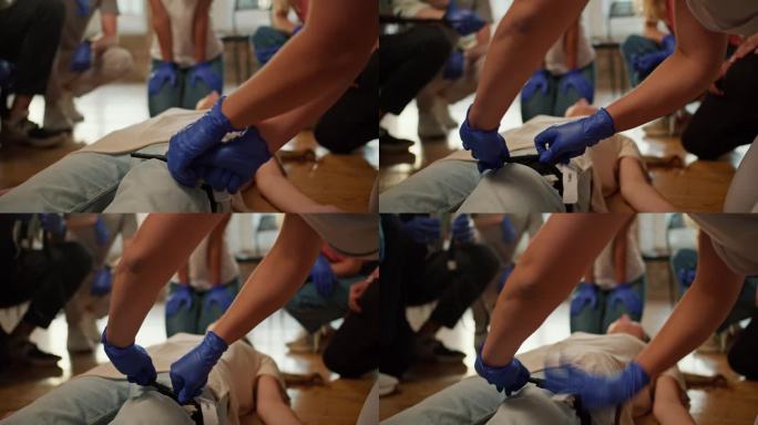 特写镜头:一名身穿白色医疗制服的专业护士正在给一个人的腿绑上止血带，并在急救训练中向公众授课