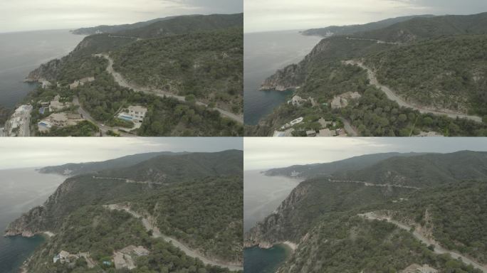 无人机拍摄的两辆跑车行驶在漫长曲折的山路上，在一个灰色的一天在意大利的一个湖泊或海洋附近