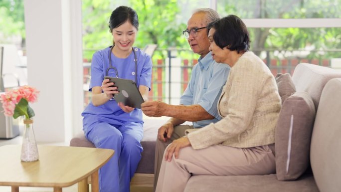 专业的亚洲护士或医生在老年保健中心诊所或医院的客厅为老年夫妇使用片剂进行咨询和辅助。
