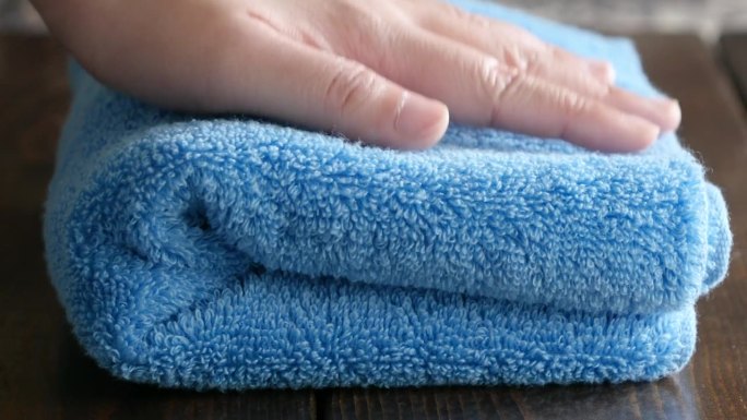 一段蓝色浴巾被手工揉松和按压的视频。